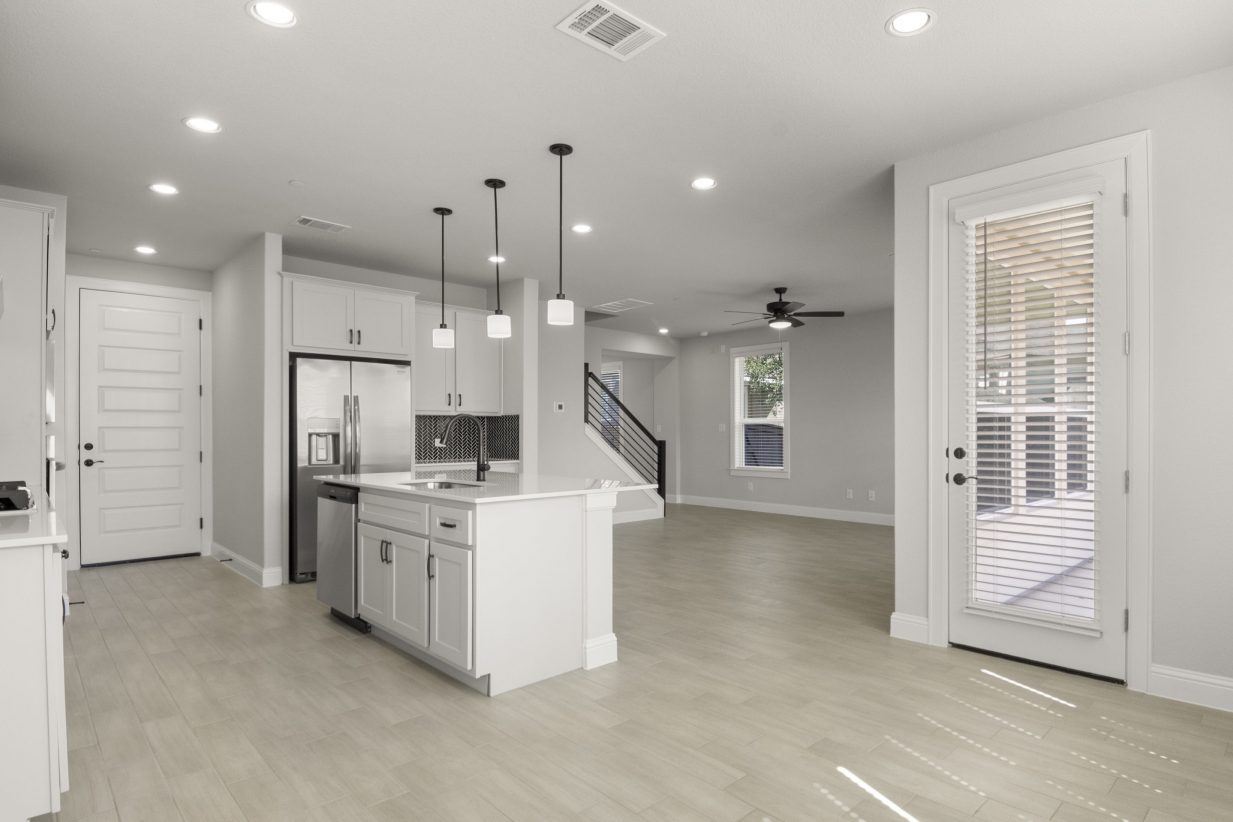 Kitchen and dining room interior with white countertop kitchen island and tan vinyl flooring.