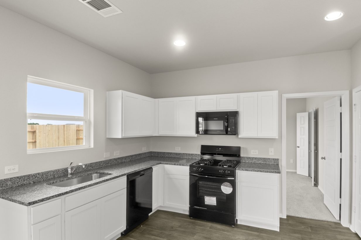 Image of kitchen with white cabinets, window over sink, and wood-look floor