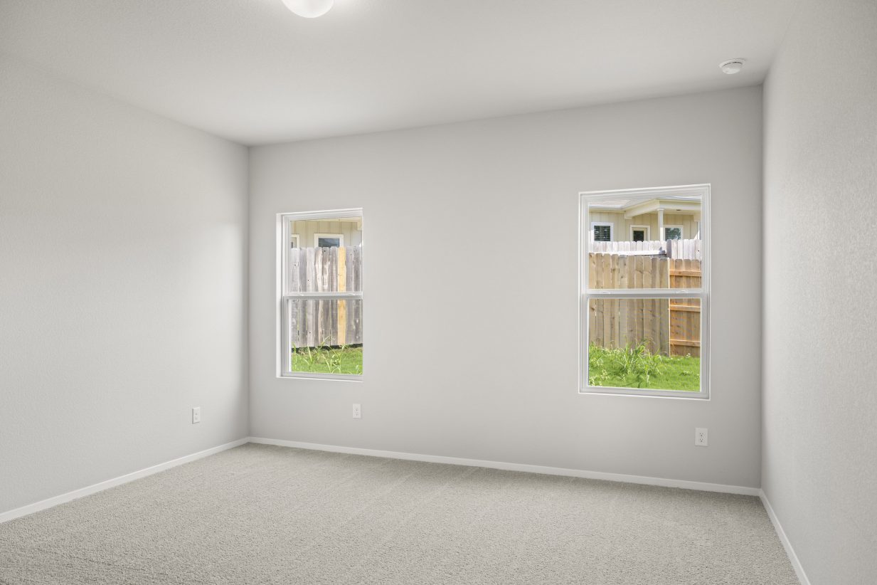 A bedroom with white painted walls, white-framed windows, and brown carpet.