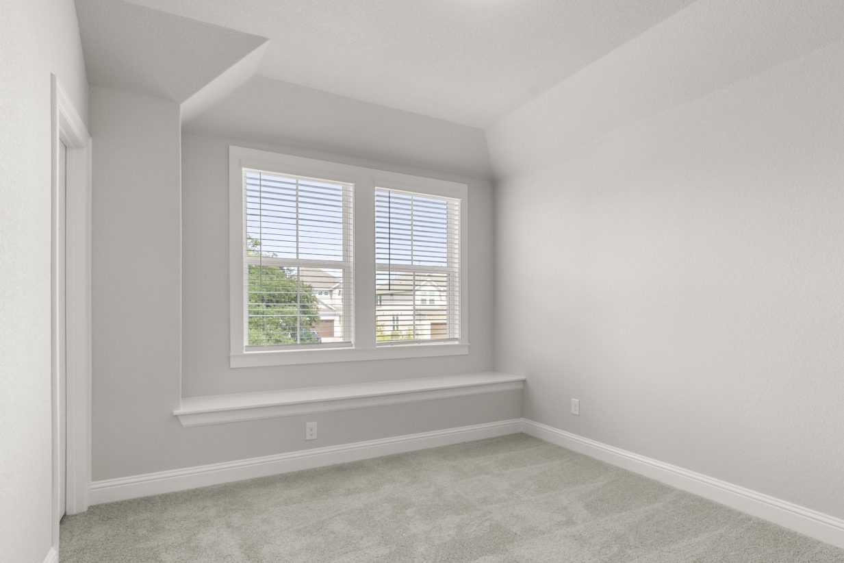 A bedroom with tan carpet, white walls, and white-framed window.