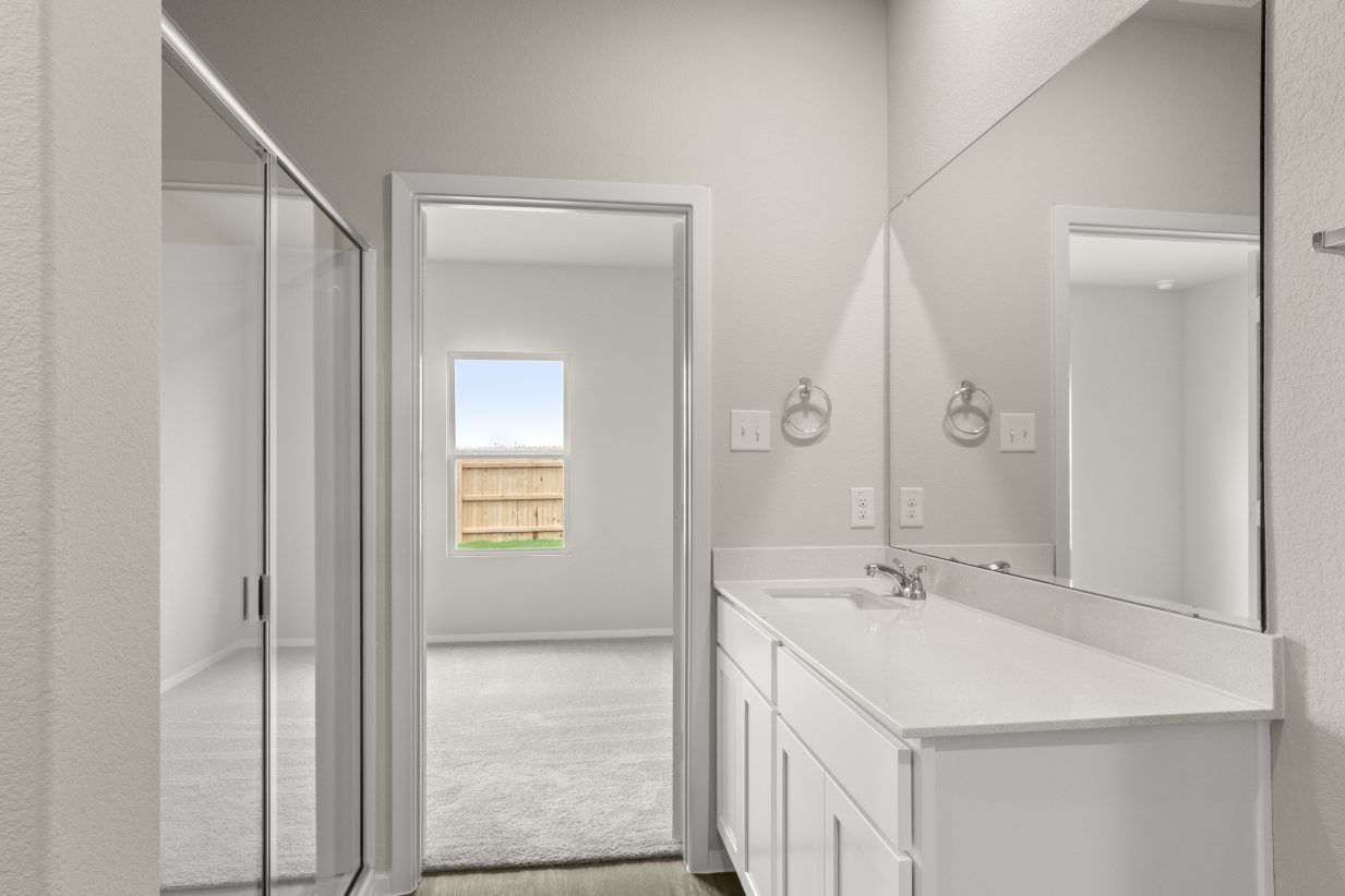 Image of en-suite bathroom with white vanity and cabinets on right and walk-in shower on left