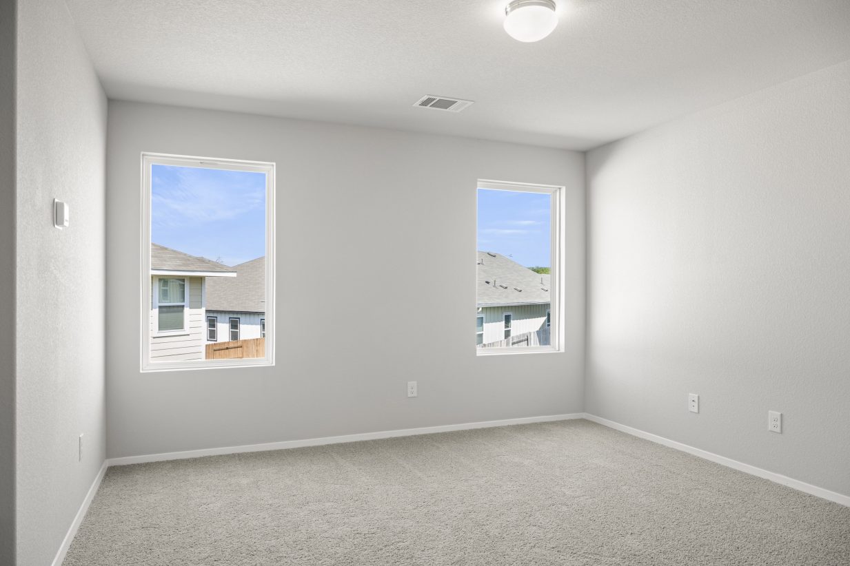 A flex space with white painted walls, white-framed windows, and brown carpet.