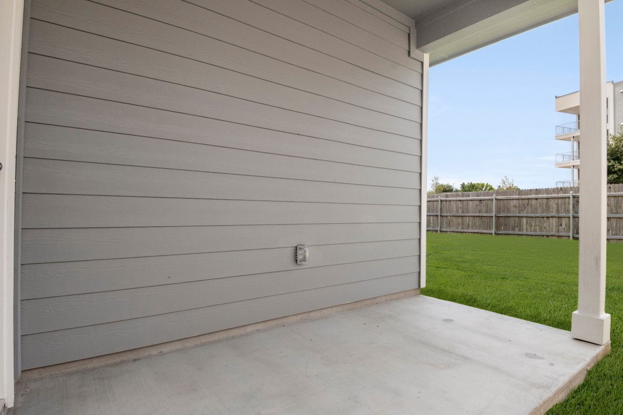 A covered patio with green grass.