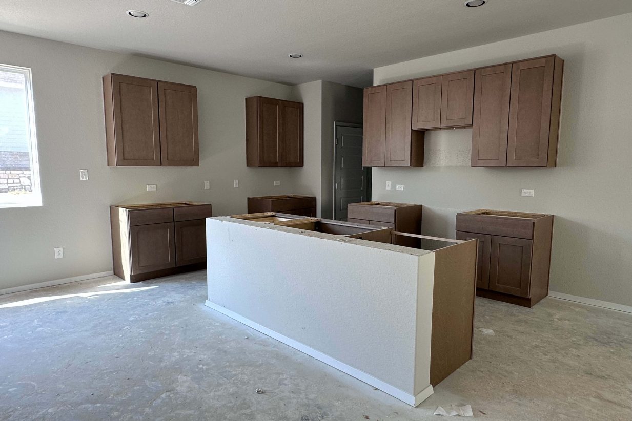 An image of kitchen under construction with brown cabinets and cream painted walls.