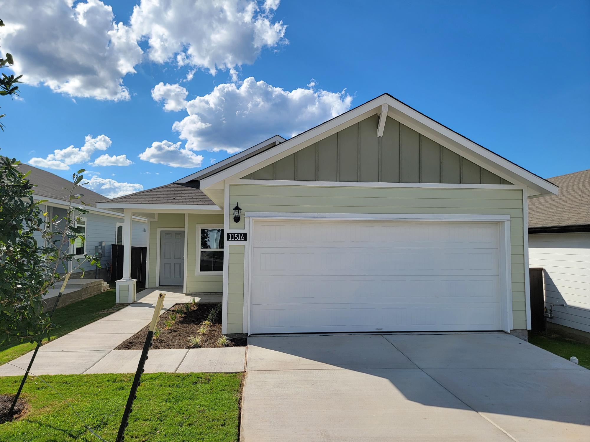 Image of one story yellow home with white accents and garage, green grass, and sky