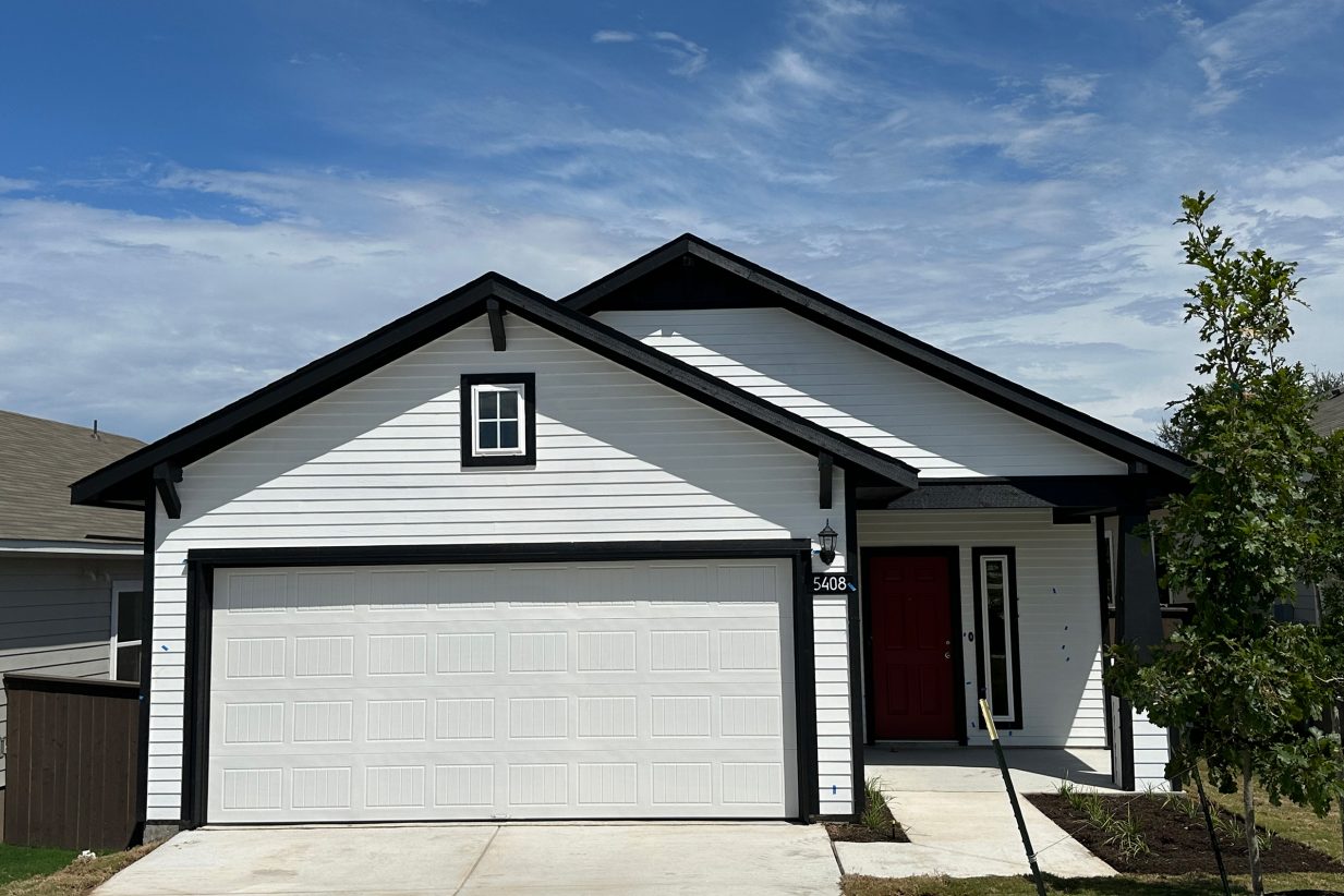 Image of one story white and black home with white garage and red front door