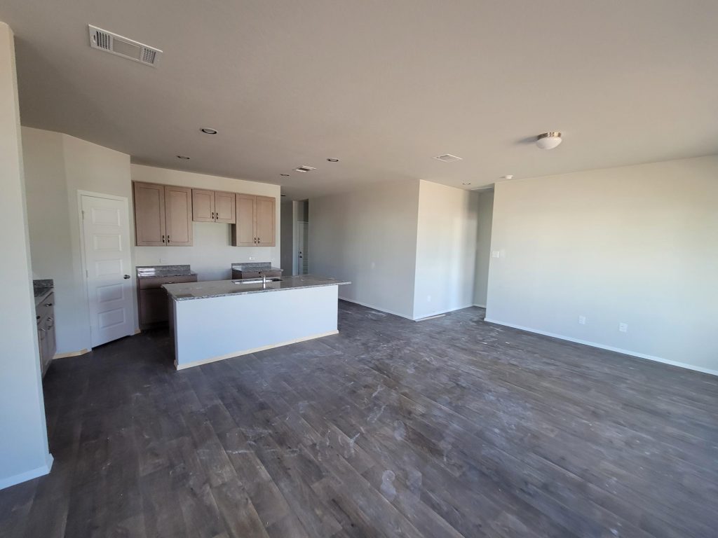 Image of home living and kitchen with wood look floor, light brown cabinets, and white walls