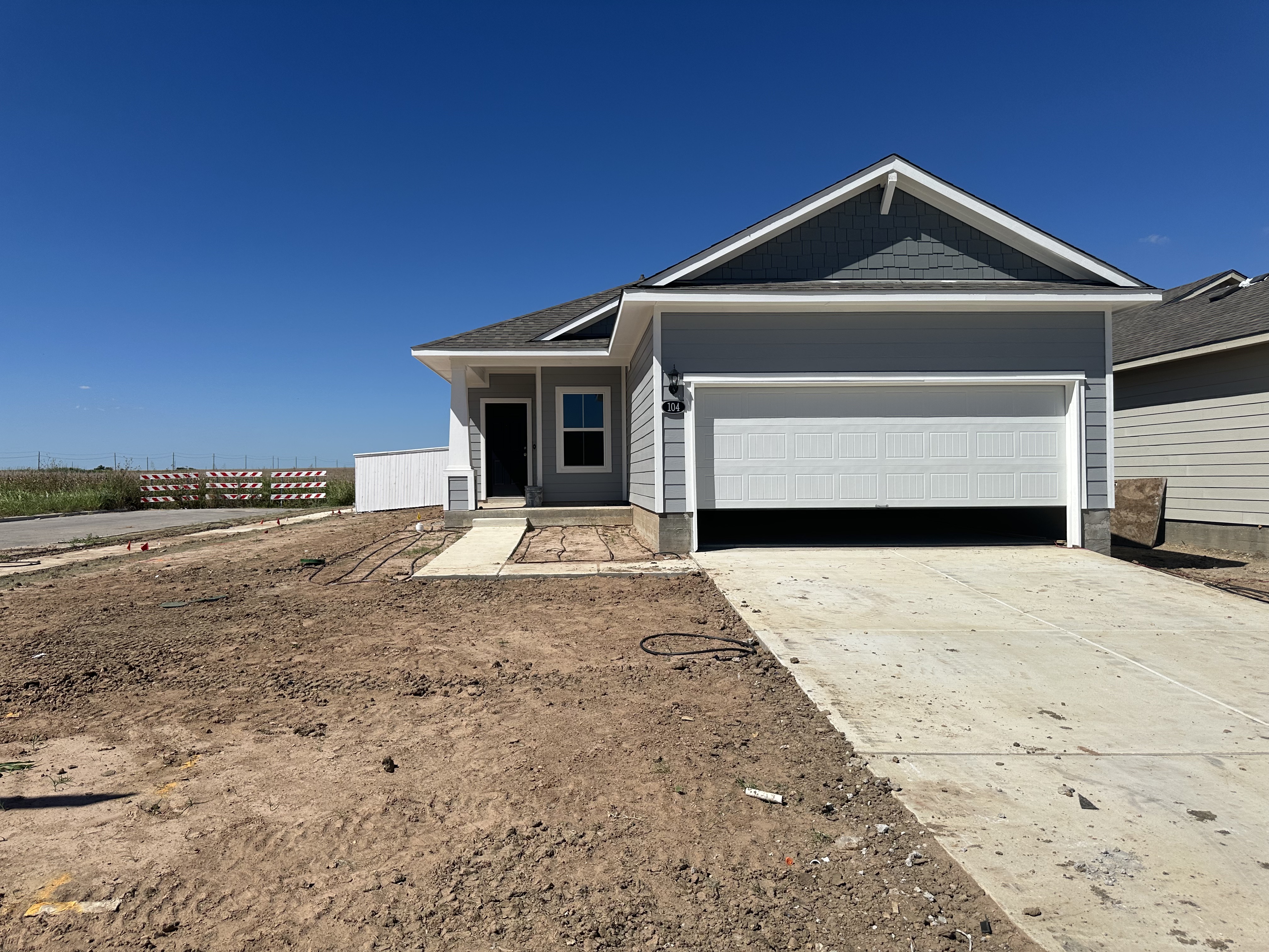 Image of exterior of one story blue home of a corner lot without grass