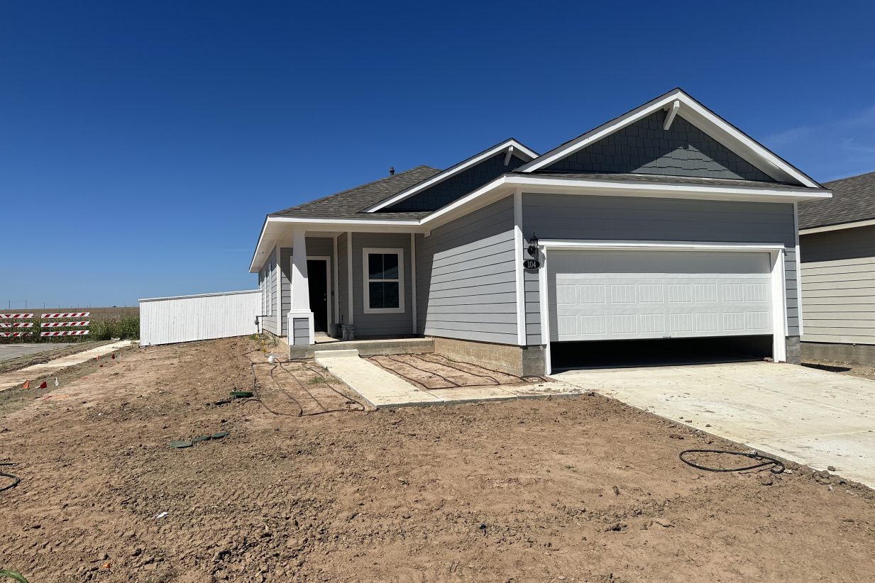 Image of corner view of front exterior of blue, one story home