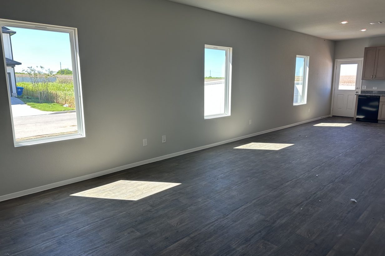 Image of home living room with 3 windows and wood-look vinyl flooring