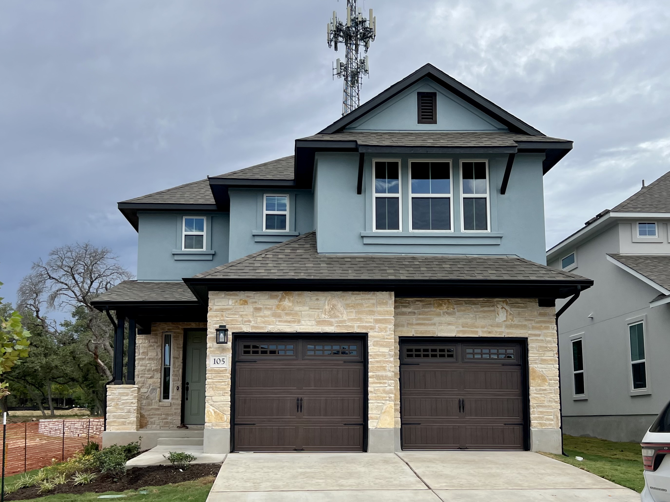 Front exterior of a blue two-story house with a double brown garage and driveway.